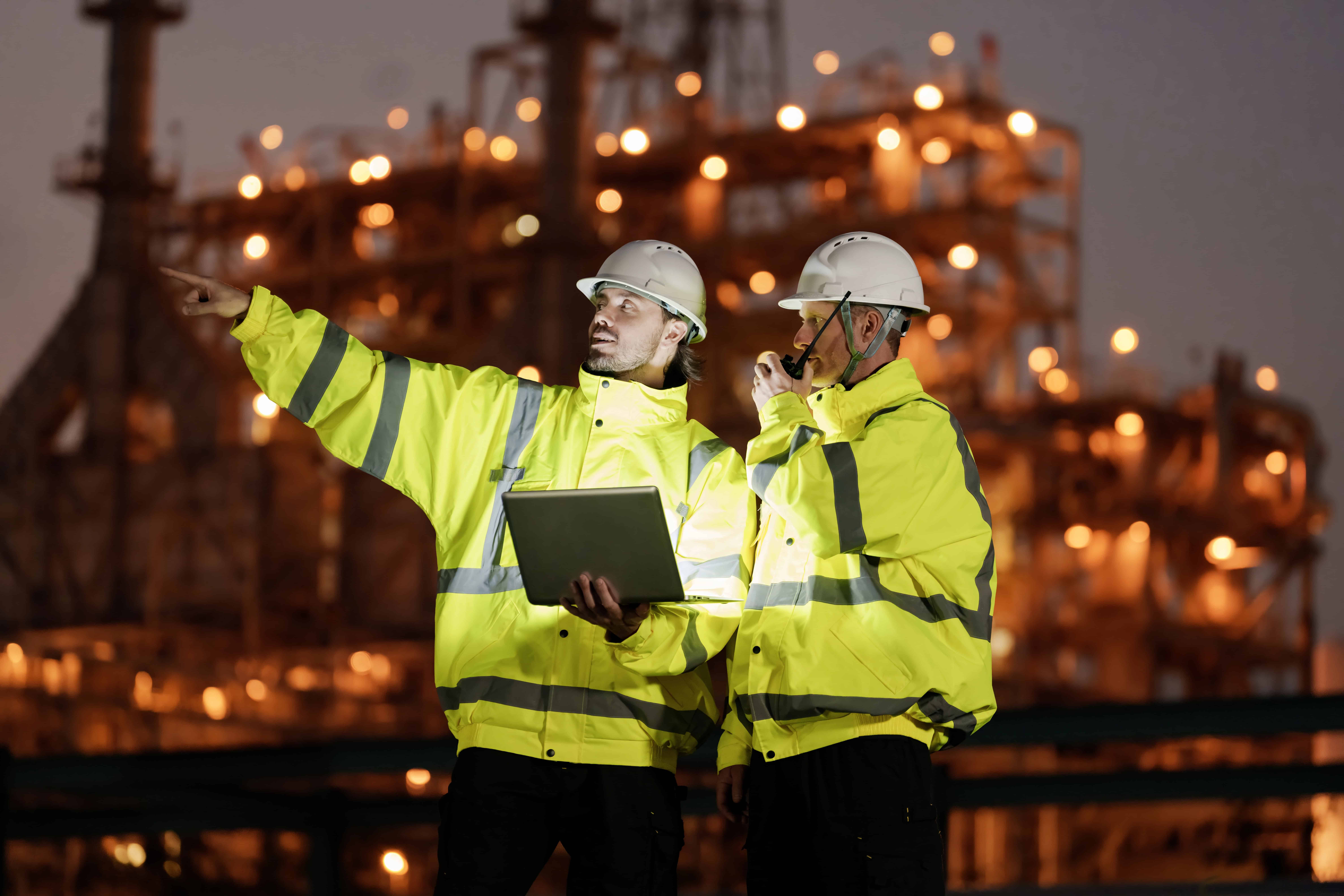 Two engineers reviewing data at an offshore facility at night, where recovery status is unknown and critical decisions carry hidden risk.