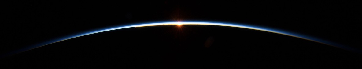 Small bit of light/sun shining over earths horizon