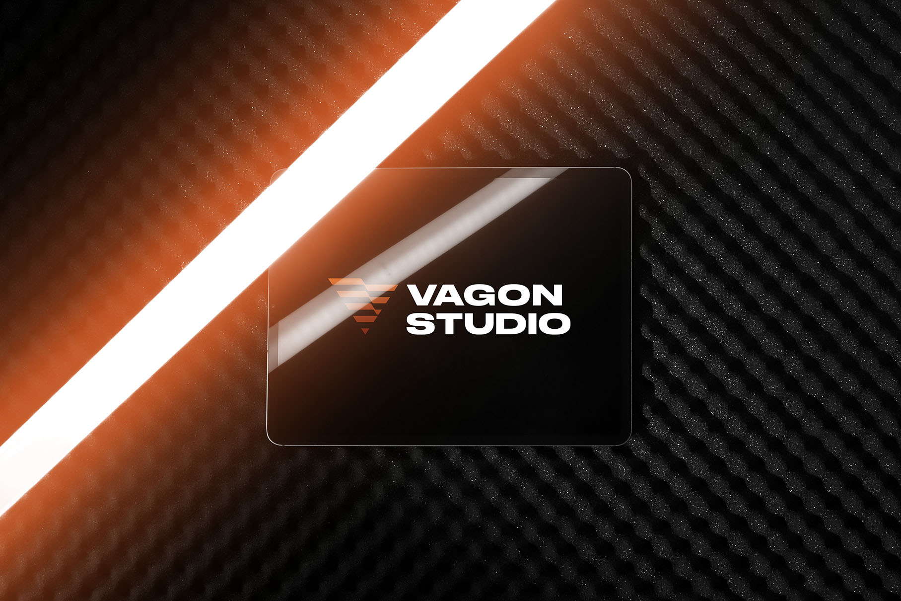 Zdjęcie tabletu z logo Vagon Studio z pomarańczowym neonem