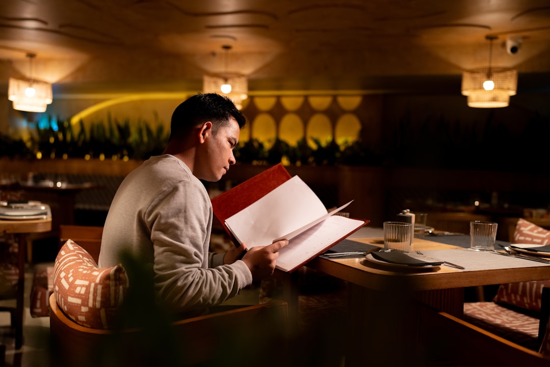 Man reading a menu at a restaurant table.