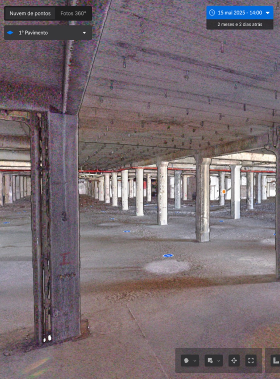 Captura de tela da plataforma Visi by Construct IN exibindo o interior de um grande pavilhão industrial através de uma nuvem de pontos. O teto e os pilares de concreto são visíveis com marcas azuis no chão indicando os pontos onde foram feitas as Capturas da Realidade em 360°.