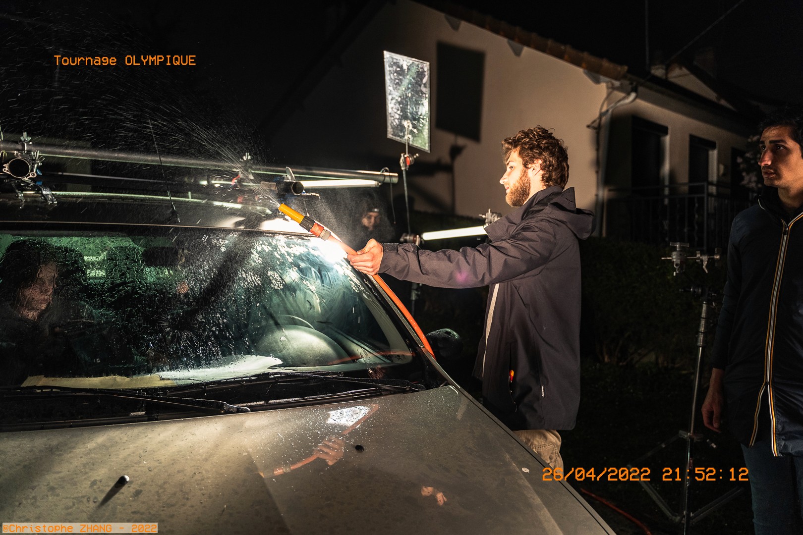 Technicien simulant la pluie sur un pare-brise pour une scène nocturne.