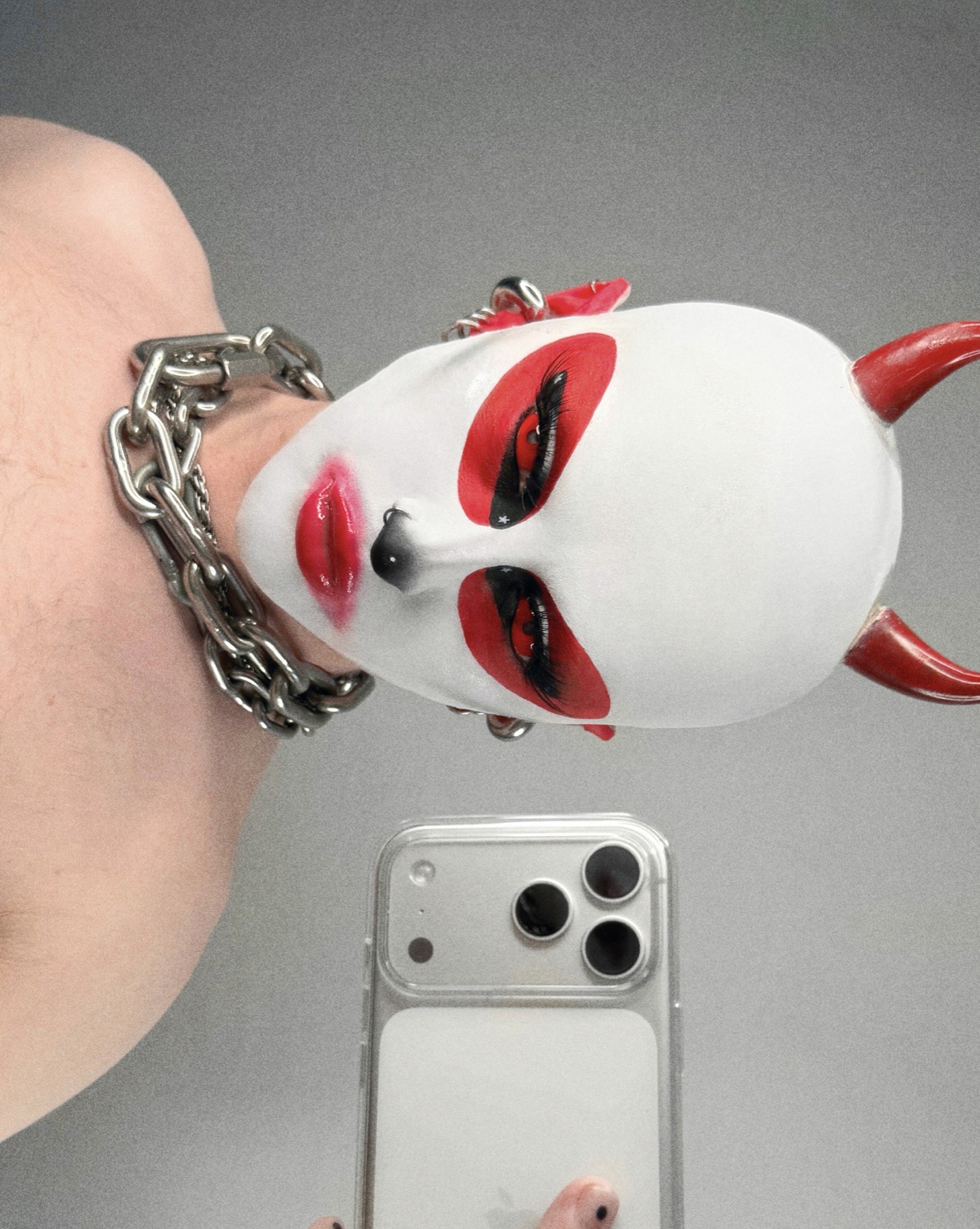 Sideways mirror selfie of Bo Quinn with red oval eye makeup, red horns and silver chains