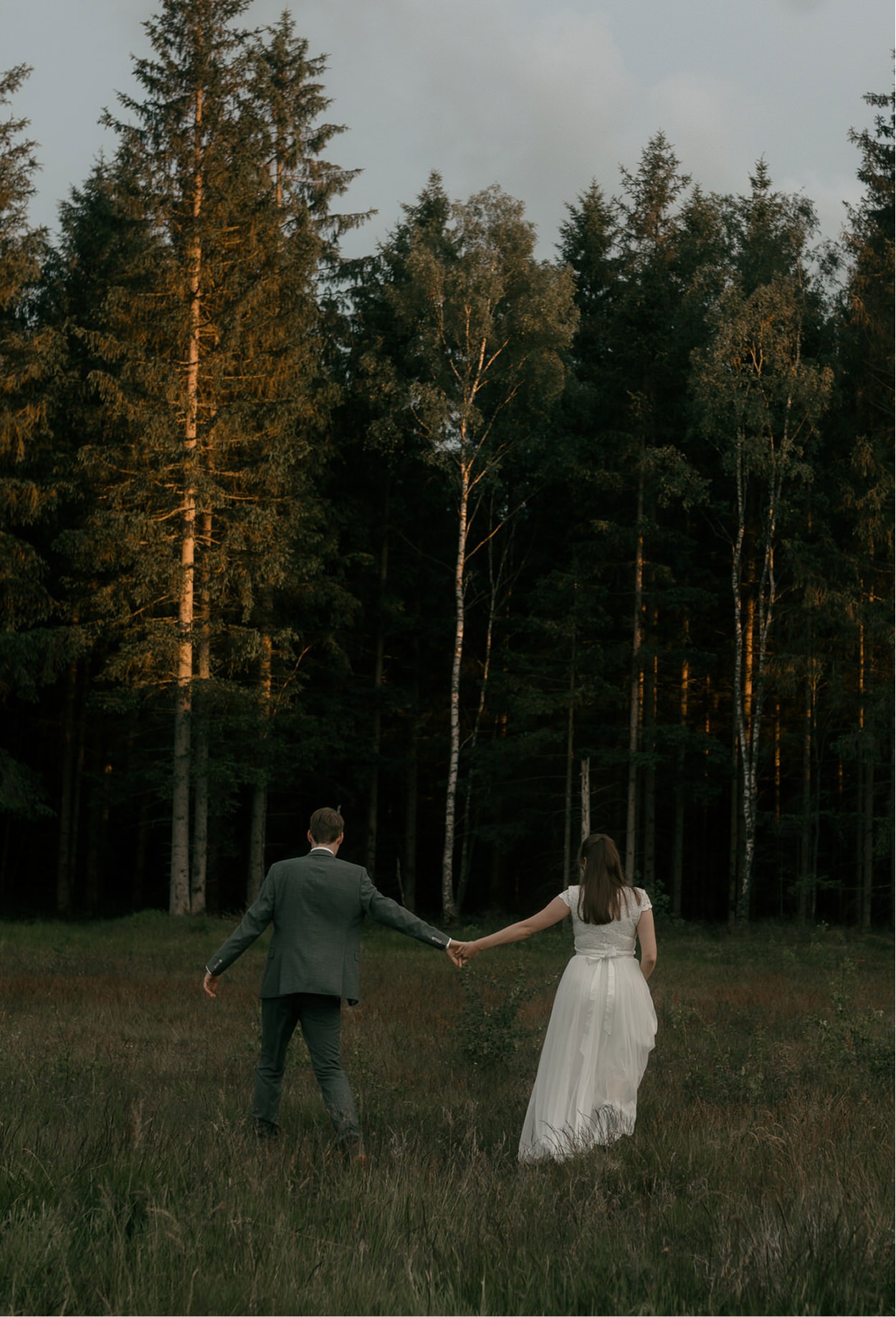 Wedding couple under veil with sunlight illuminating brides ice blue eyes