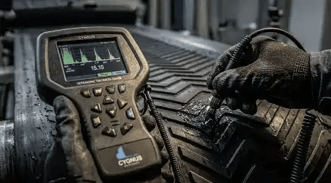 Glospech technician using Cygnus 1 EX intrinsically safe ultrasonic thickness gauge to measure wall thickness through rubber lagging on mining conveyor pulley