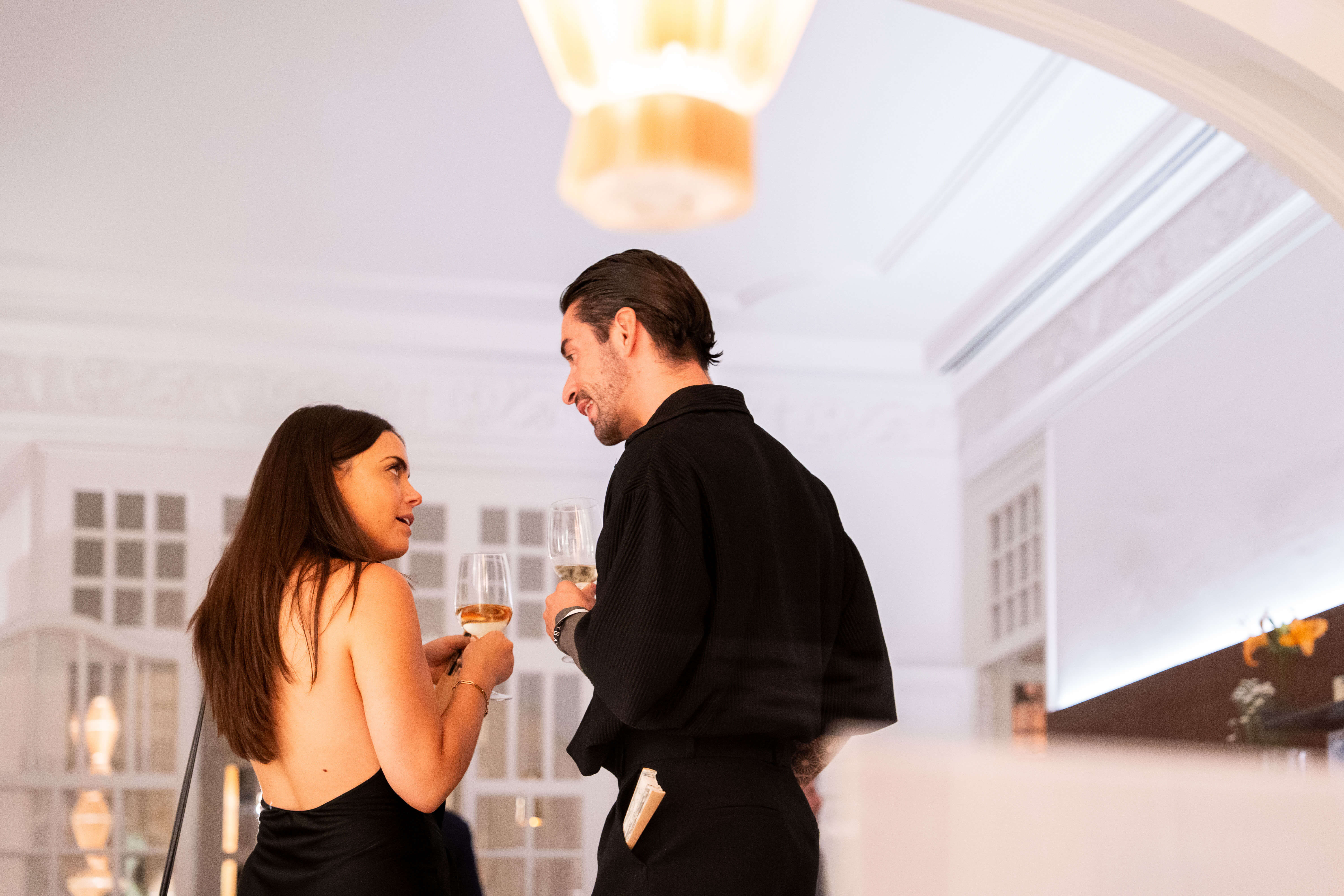 Dos personas conversando en un evento con una copa de vino en la mano