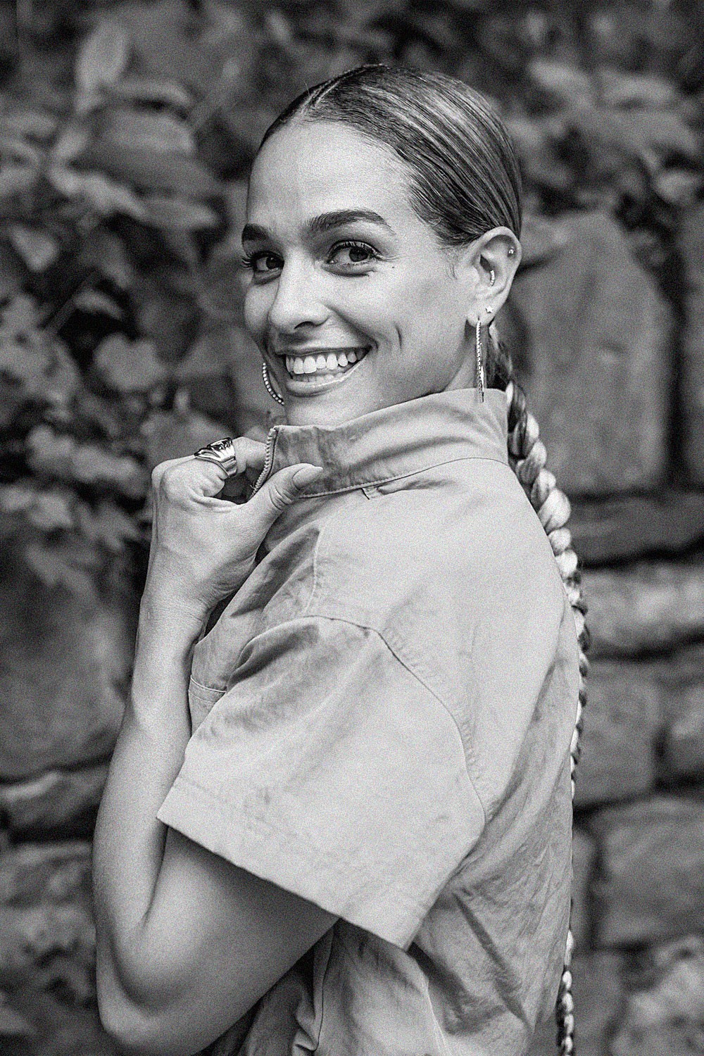 Smiling person with curly hair, wearing a black shirt, against a warm, dark background.