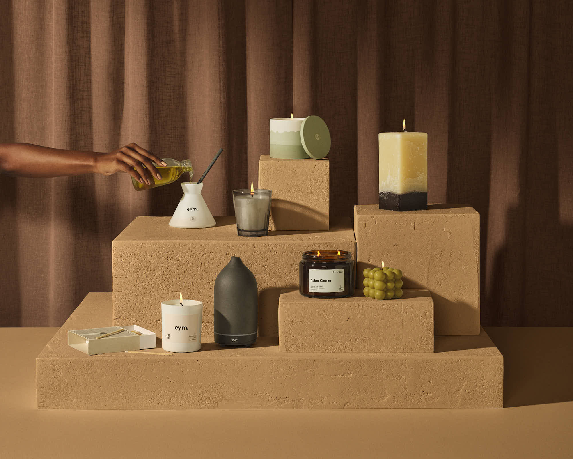 Stylish scented candles and home decor on minimalist brown display.