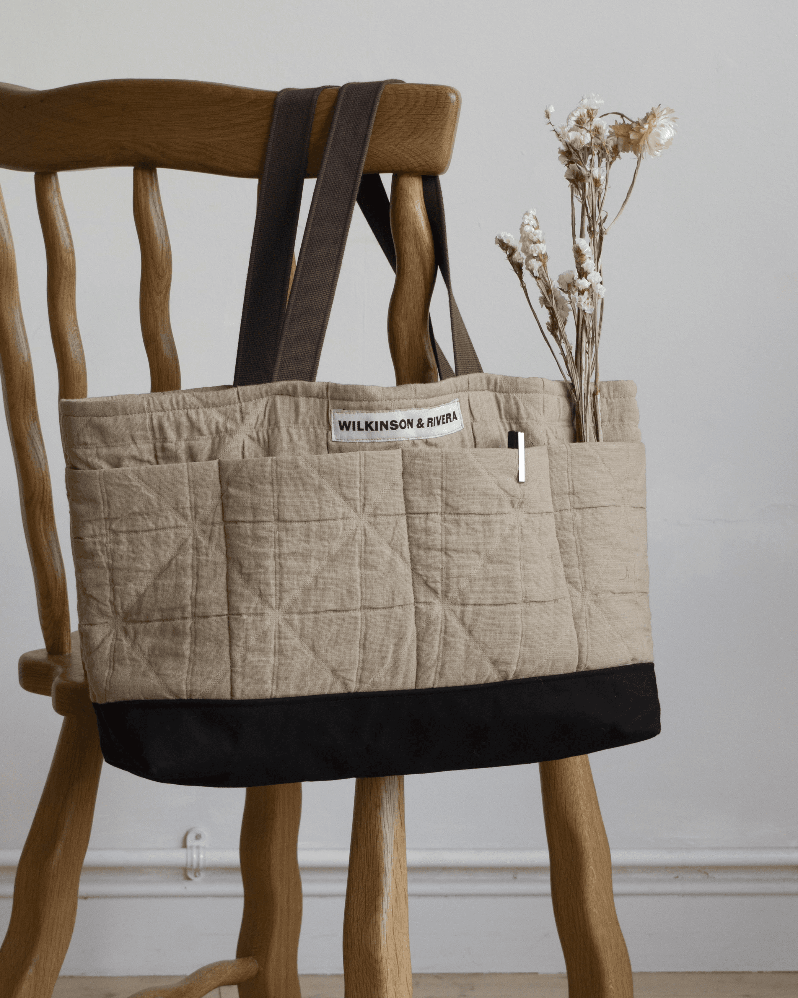 Limited edition Garden Tote from Wilkinson & Rivera in Cotton Jacquard hanging from chair with flowers in one pocket and a pen in another.