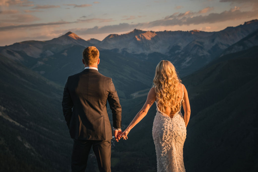 Newlyweds holding hands while overlooking a Colorado mountain valley.
