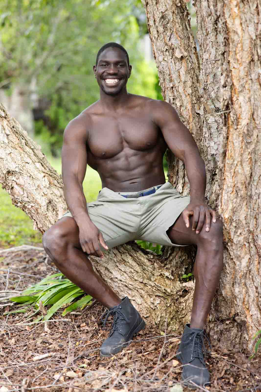 Shirtless man sitting in tree