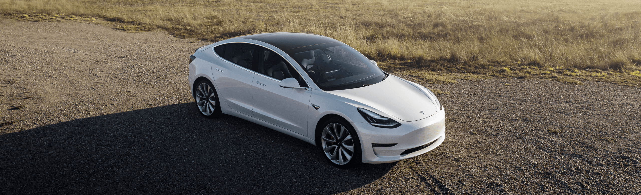 Tesla Model 3 blanche vue du dessus dans un décor de campagne, berline électrique stationnée en pleine nature