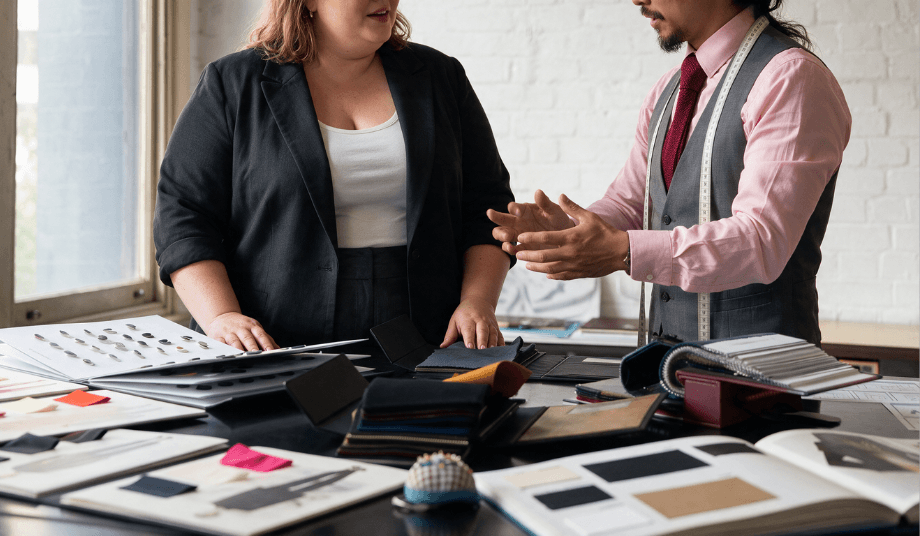 Bespoke plus size masculine suit consultation showing fabric swatches, button books, and design discussion