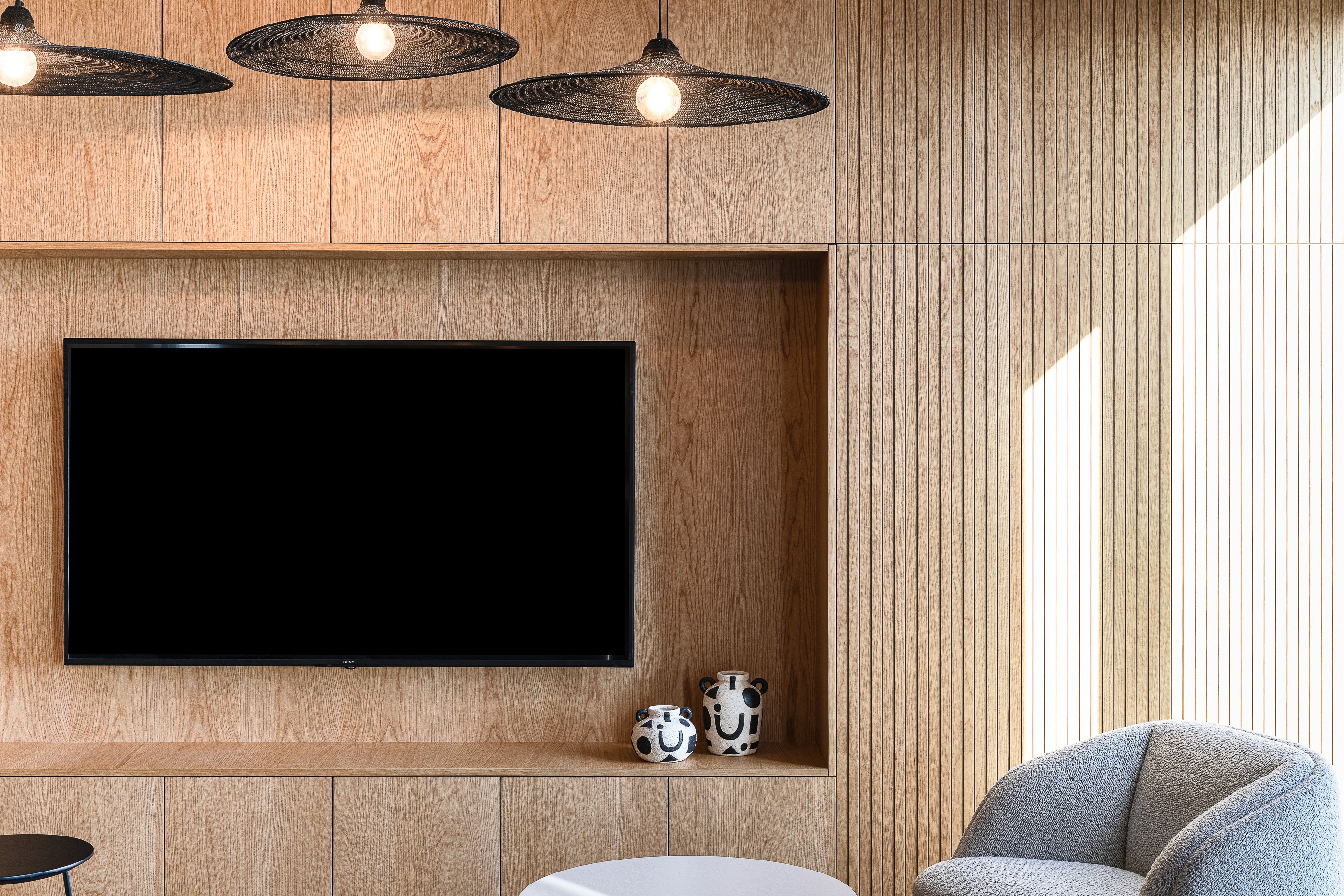 פרט נגרות: שילוב מסך מולטימדיה בתוך חיפוי עץ אלון טבעי בקו-אפס, המעניק מראה נקי ואלגנטי לאזור ההתכנסות.