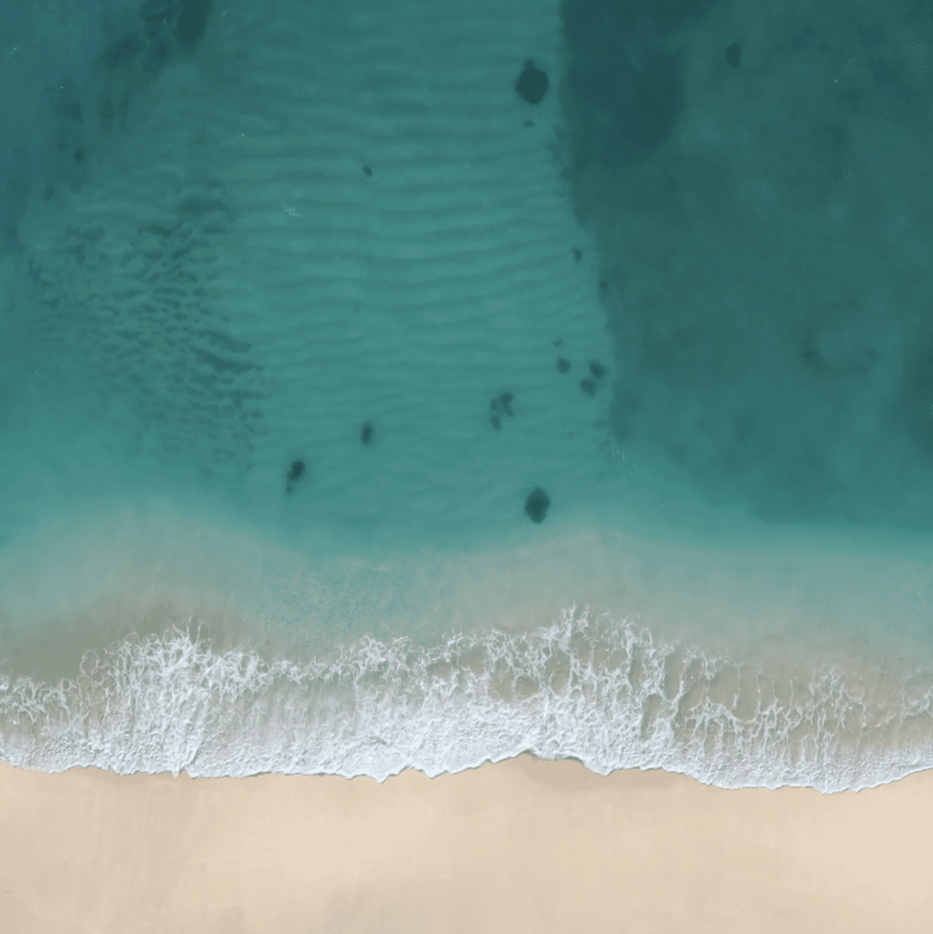 Turquoise ocean shoreline seen from above, reflecting Only Maldives’ serene luxury escapes