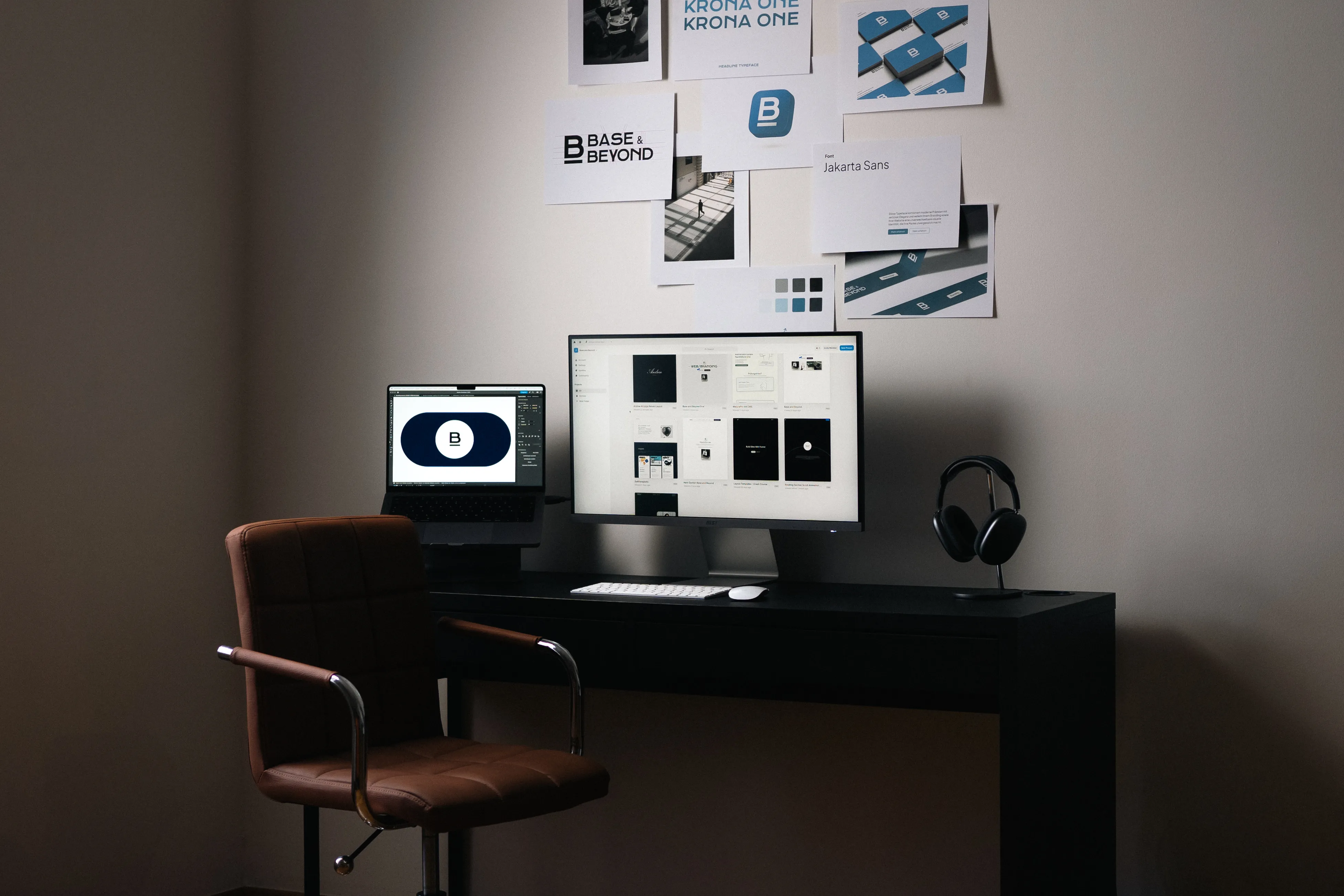 Schreibtischarbeitsplatz mit zwei Monitoren, einer davon zeigt das  Logo von Base and Beyond. An der Wand hängen Branding-Entwürfe, Farben, Typografie und Logos – kreative Arbeitsumgebung für UX/UI-Design und Markenentwicklung.