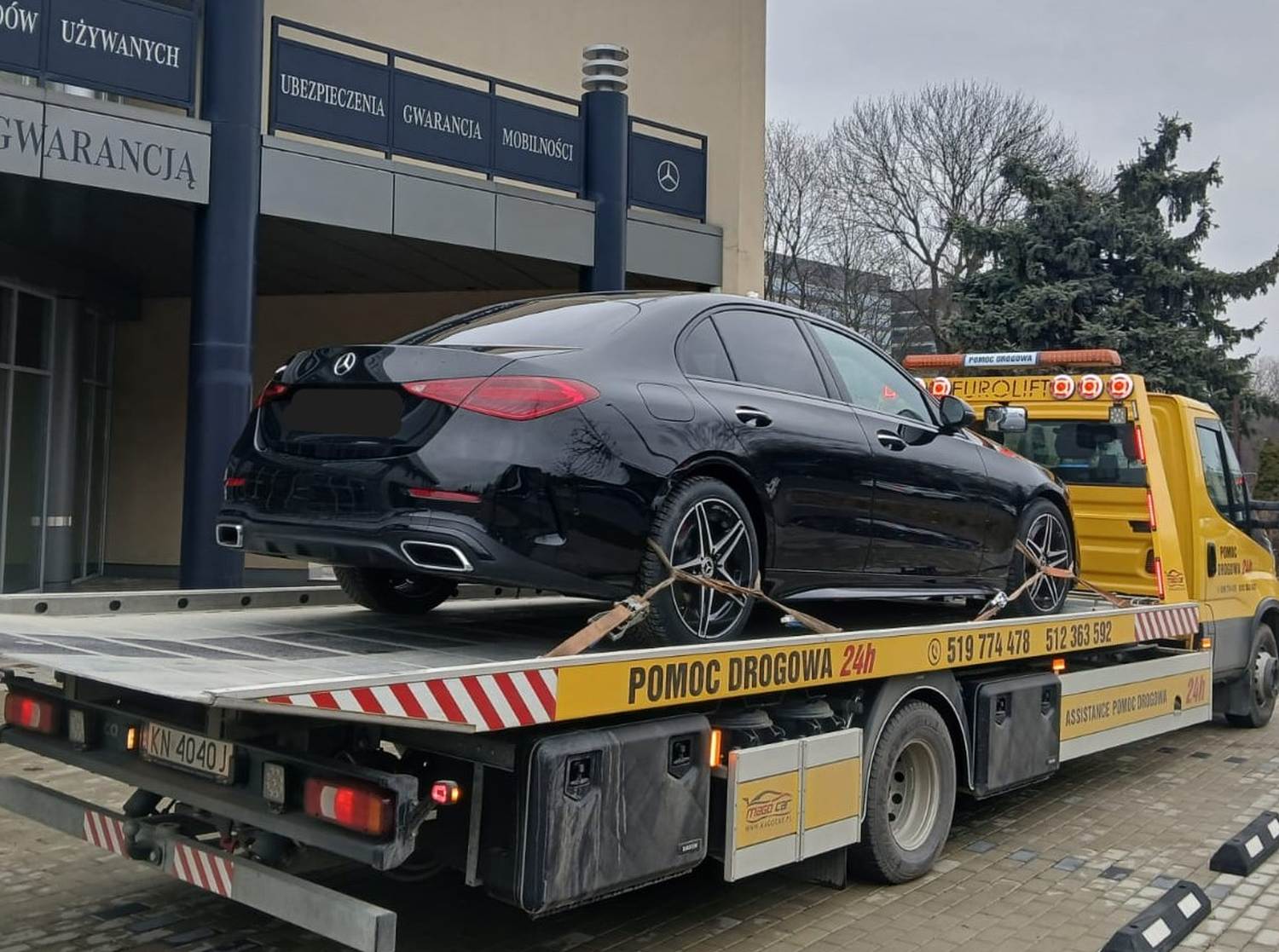 pomoc drogowa po kolizji – samochód na lawecie podczas załatwiania formalności