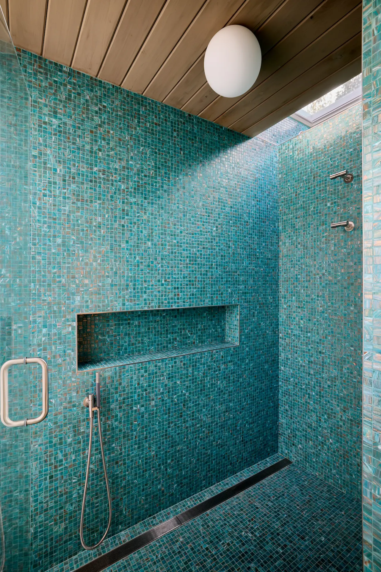 Angled portrait of the master shower with its linear drain, showcasing the meticulous attention to detail in this Eichler home remodel. Photo by Todd Huge.