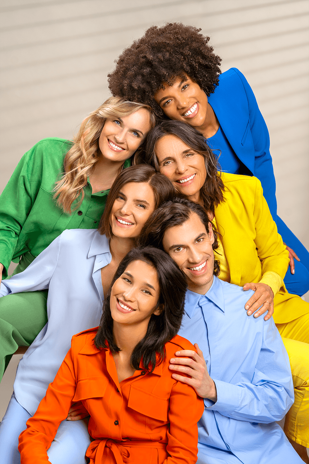 Group portrait of Croma models smiling together in colorful outfits, representing diversity and unity indoors