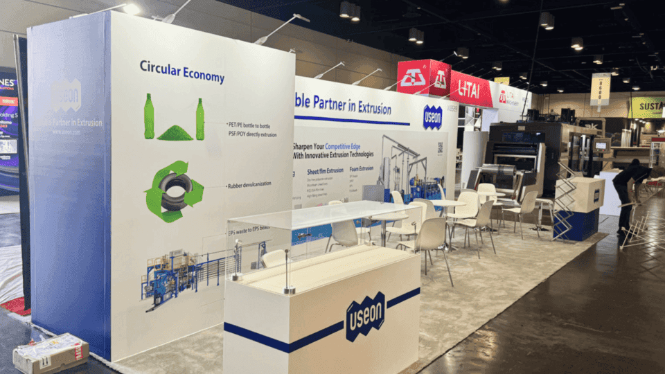 Machinery and manufacturing booth with technical product graphics, demo counter, sample display, and meeting area for industrial exhibitors