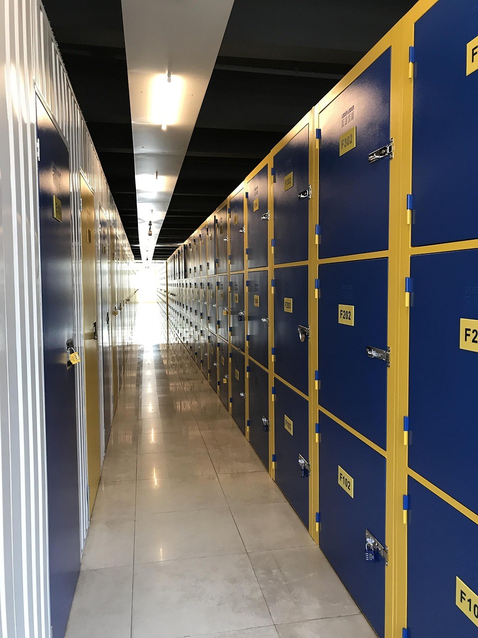 Interior hallway of a secure self-storage facility with rows of blue and yellow storage units.