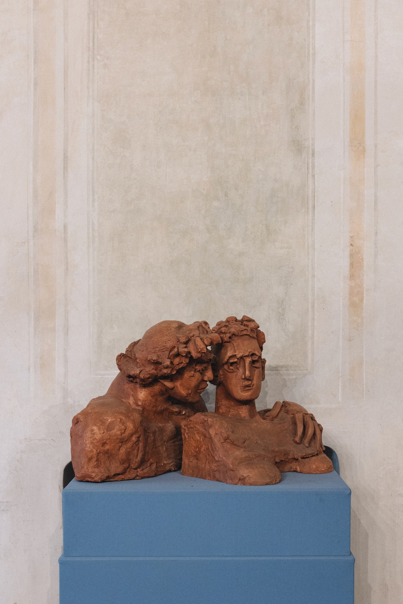 Scultura in terracotta di due volti su piedistallo blu, dettaglio artistico nel Parco di Montebello