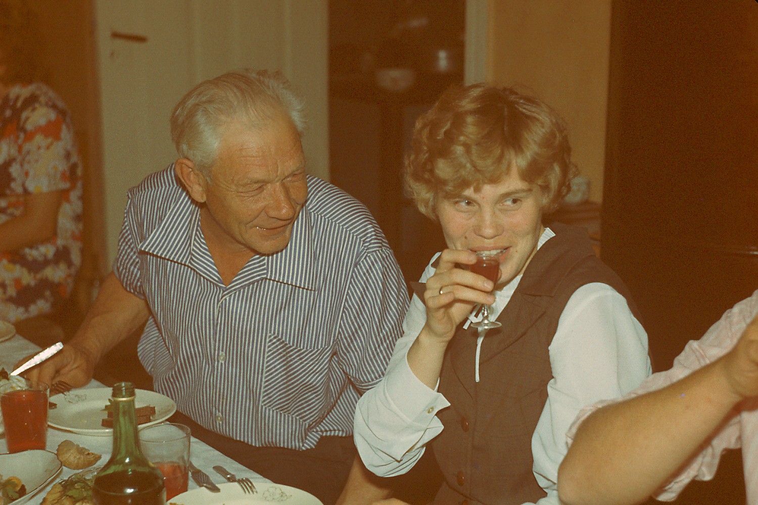 Vanem ja noorem inimene istuvad laua taga ja naeratavad