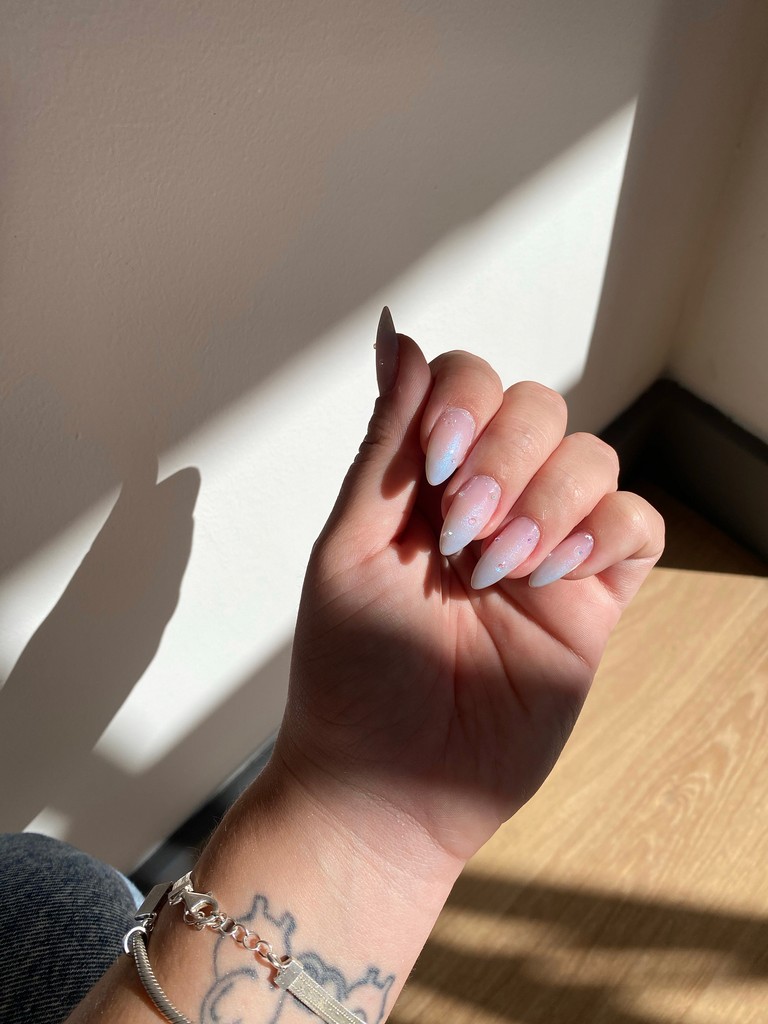 Hand with glittery pastel nails in sunlight
