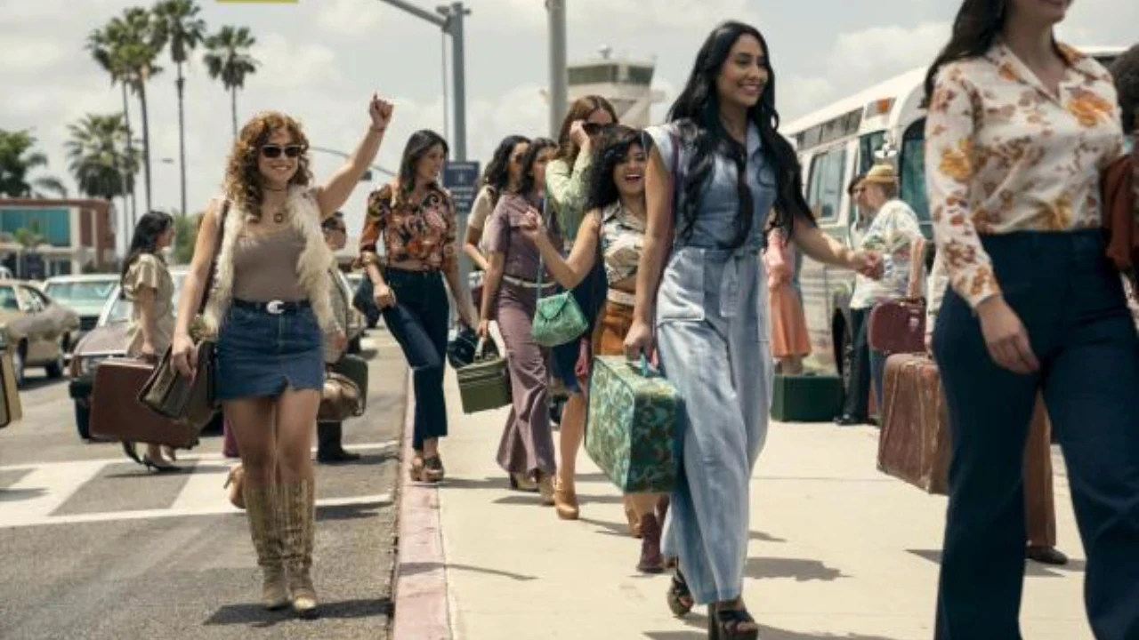 Sur un trottoir bordé de palmiers, un groupe de femmes avance ensemble en transportant des valises de différentes tailles. Elles semblent arriver ou partir d’un lieu commun, dans une ambiance ensoleillée et animée, avec un bus stationné à proximité. Cette scène visuelle accompagne la réflexion sur les espaces de travail collaboratifs et leur impact sur la productivité, en symbolisant le mouvement collectif, la coordination et l’énergie partagée au sein d’un groupe.