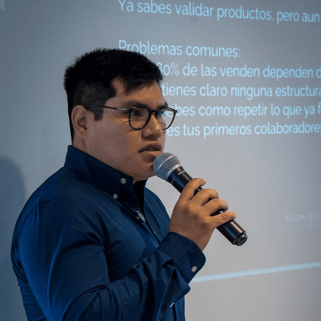 Woman in sunglasses poses against vibrant red background, wearing a beige blazer and black top. Sunlight casts dynamic shadows, creating a stylish, confident mood.