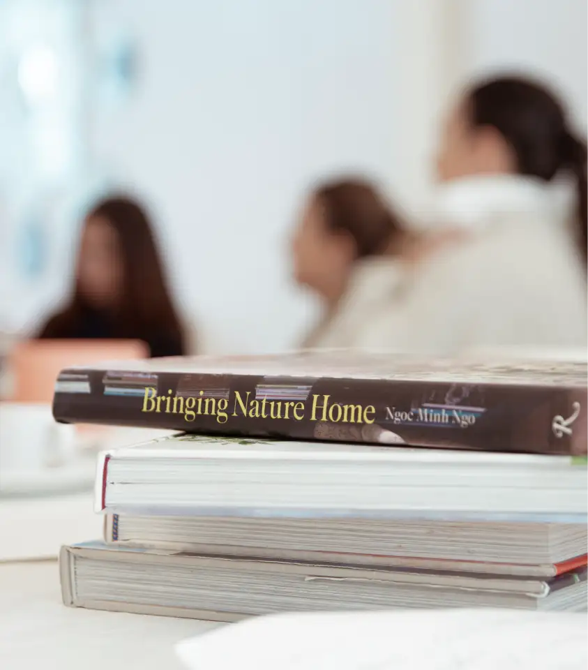 Libros de referencia sobre naturaleza y diseño floral apilados en mesa durante un workshop creativo.