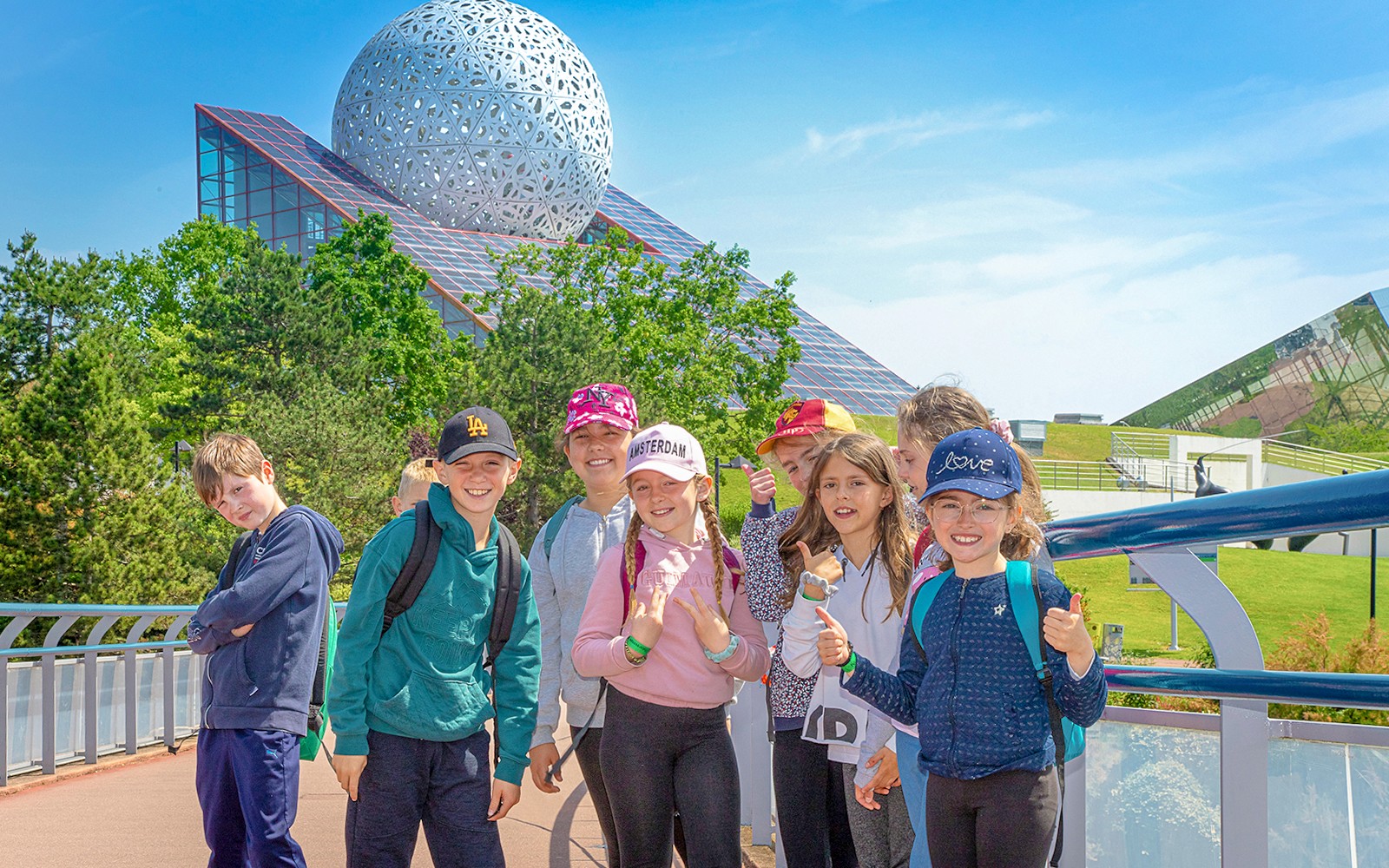 Group of children smiling in front of Futuroscope's architectural dome in France.