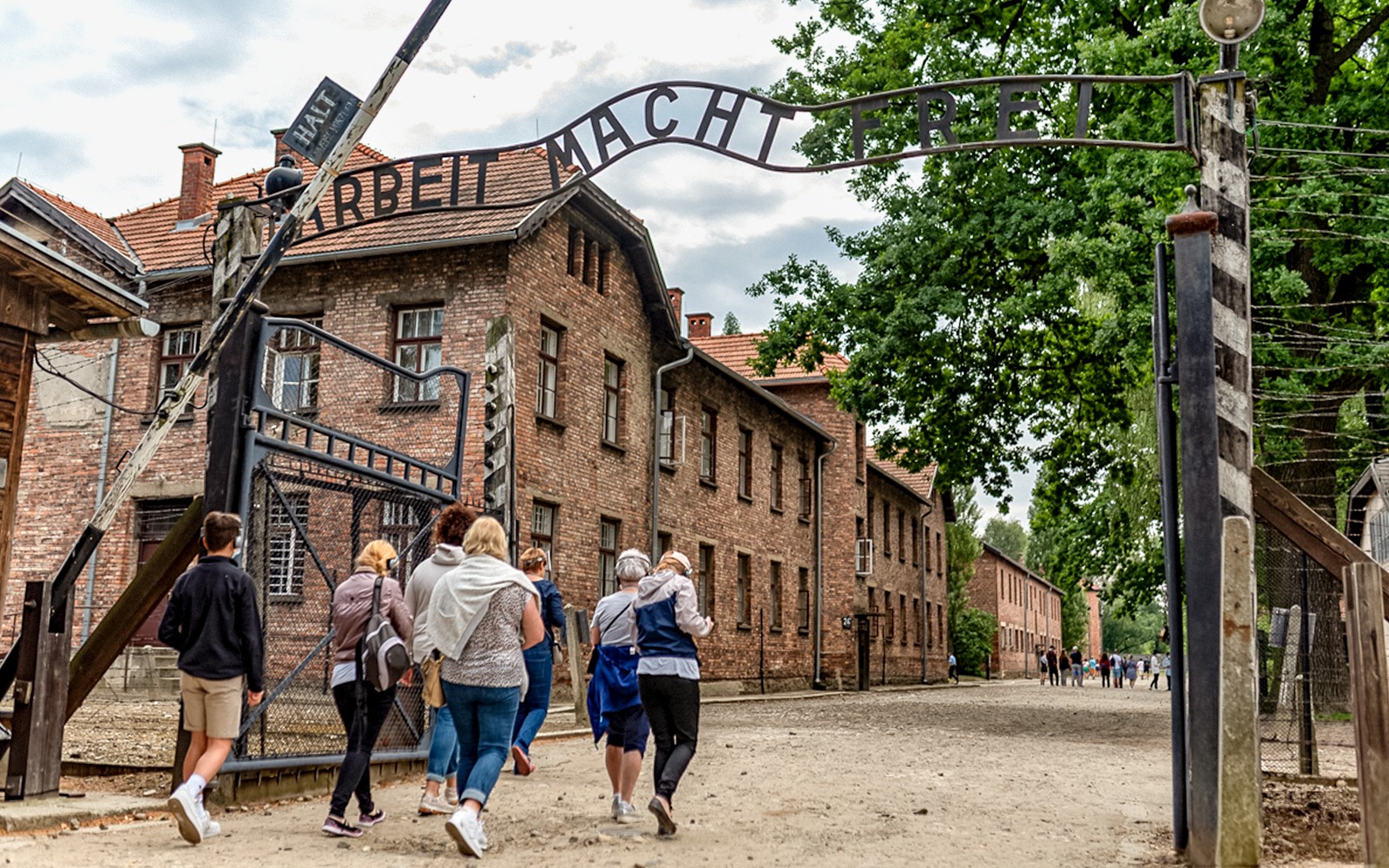 Visitatori che camminano sotto il cancello "Arbeit Macht Frei" al Campo di Concentramento di Auschwitz.