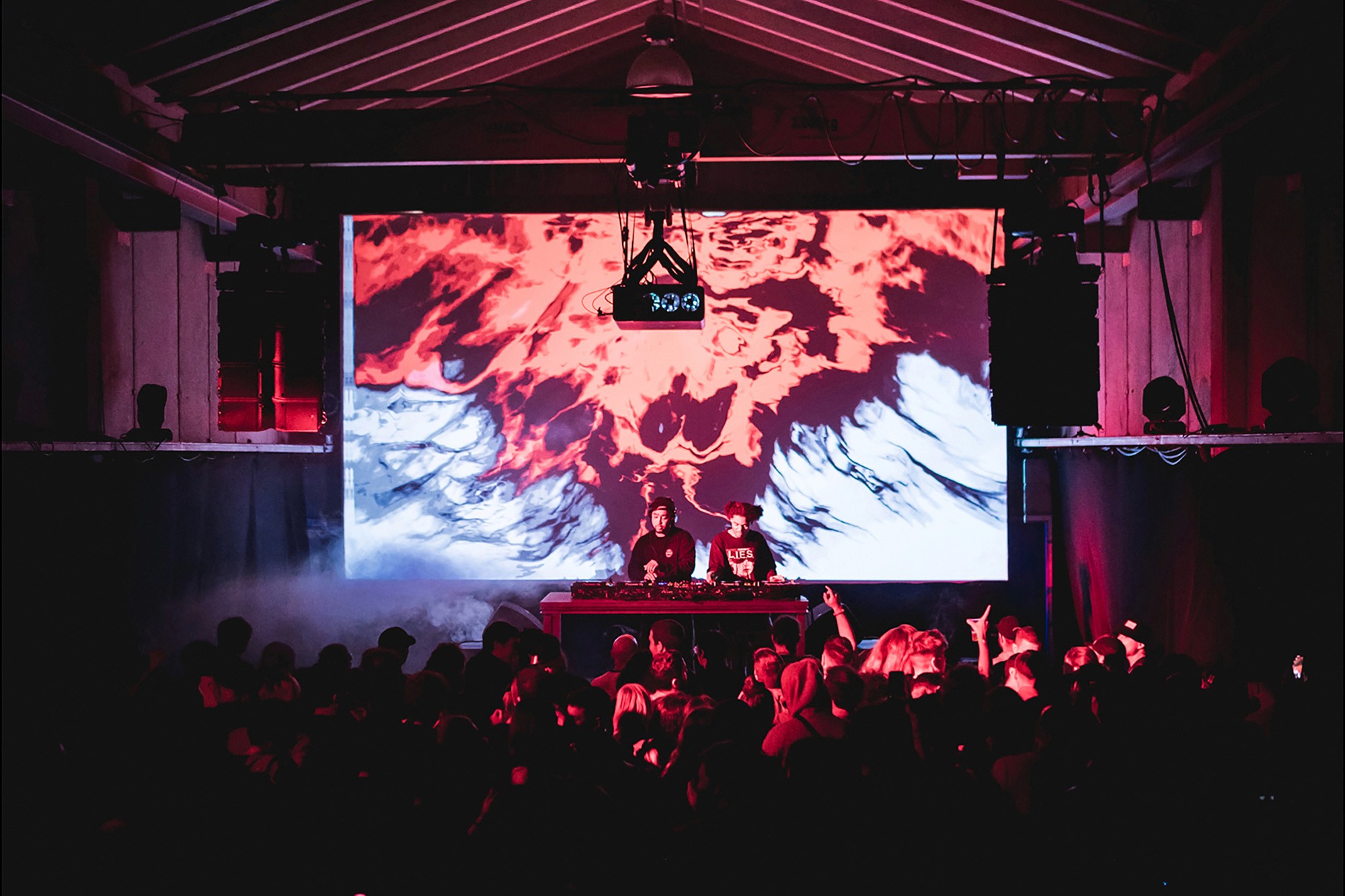 Dancing audience. Black Rave Culture group in front of a projection of texture inspired by Rorschach blots.