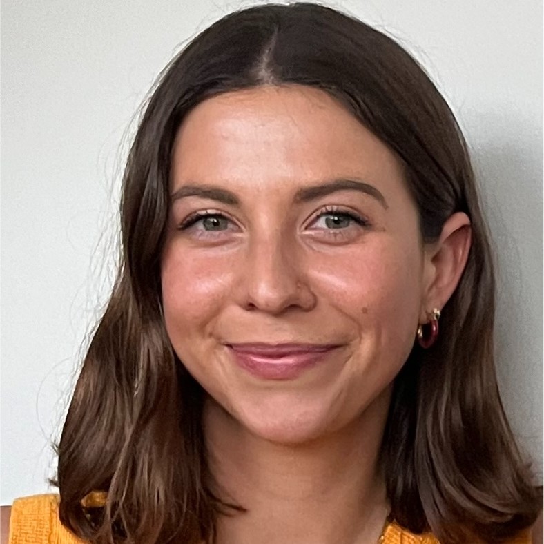 Estelle Berton, blog author, smiling at camera wearing an orange top with dark shoulder-length hair.