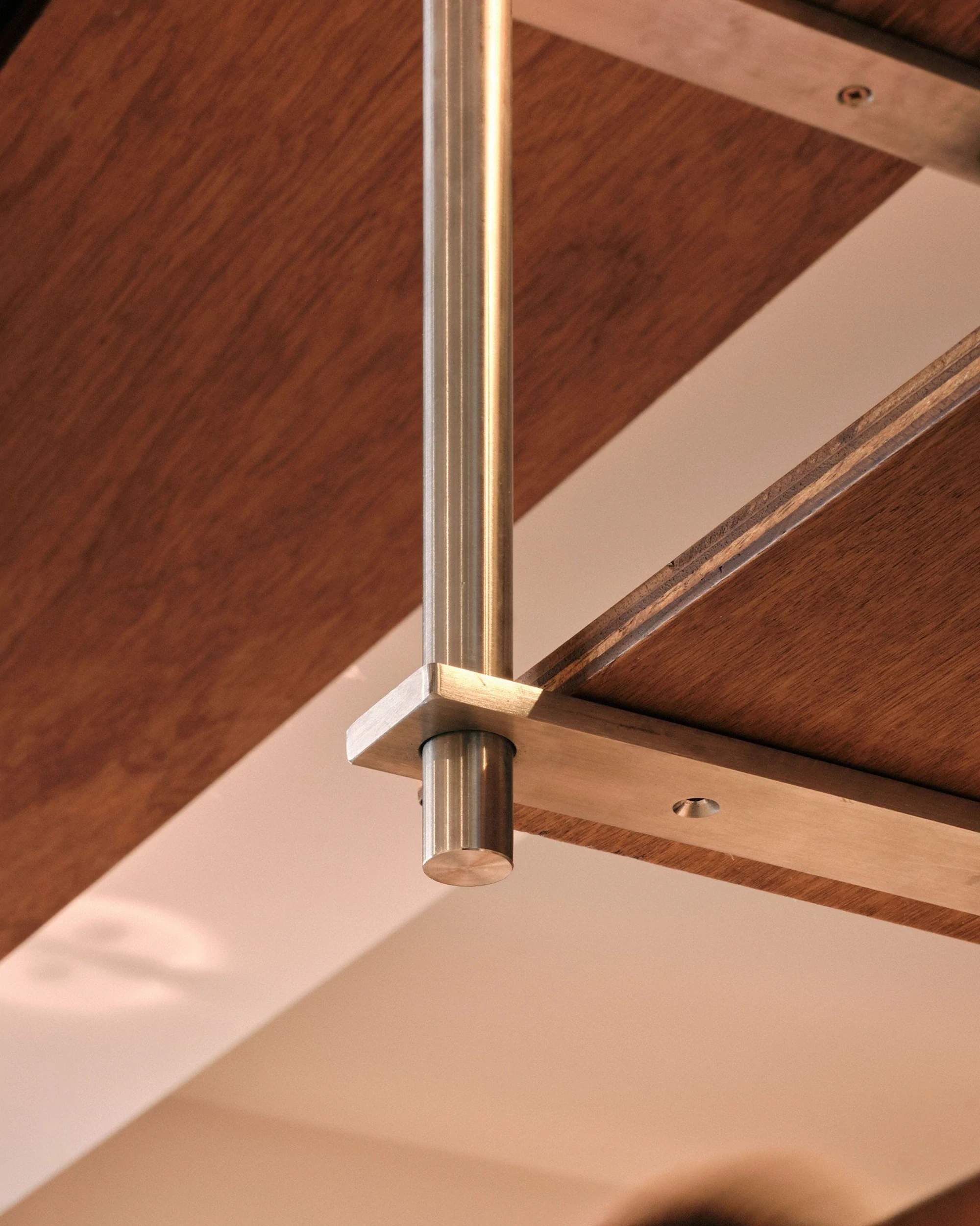 Close-up of wood cabinetry with a brass shelf bracket and soft directional lighting.