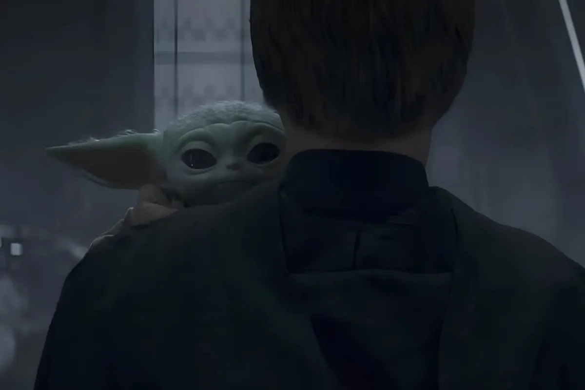 Grogu looks back with wide, emotional eyes as he rests on Luke Skywalker’s shoulder. The dim lighting and the Jedi’s dark robes contrast with Grogu’s small, vulnerable form, marking a bittersweet farewell as he leaves with his new mentor.