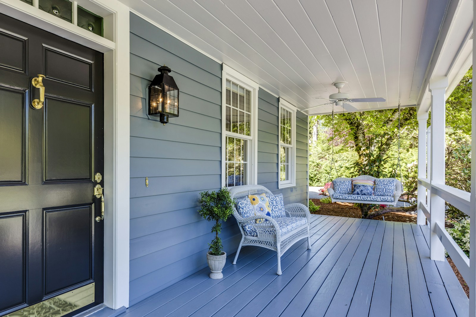 Traditional Southern blue porch with white trim, a porch swing, and a wicker chair