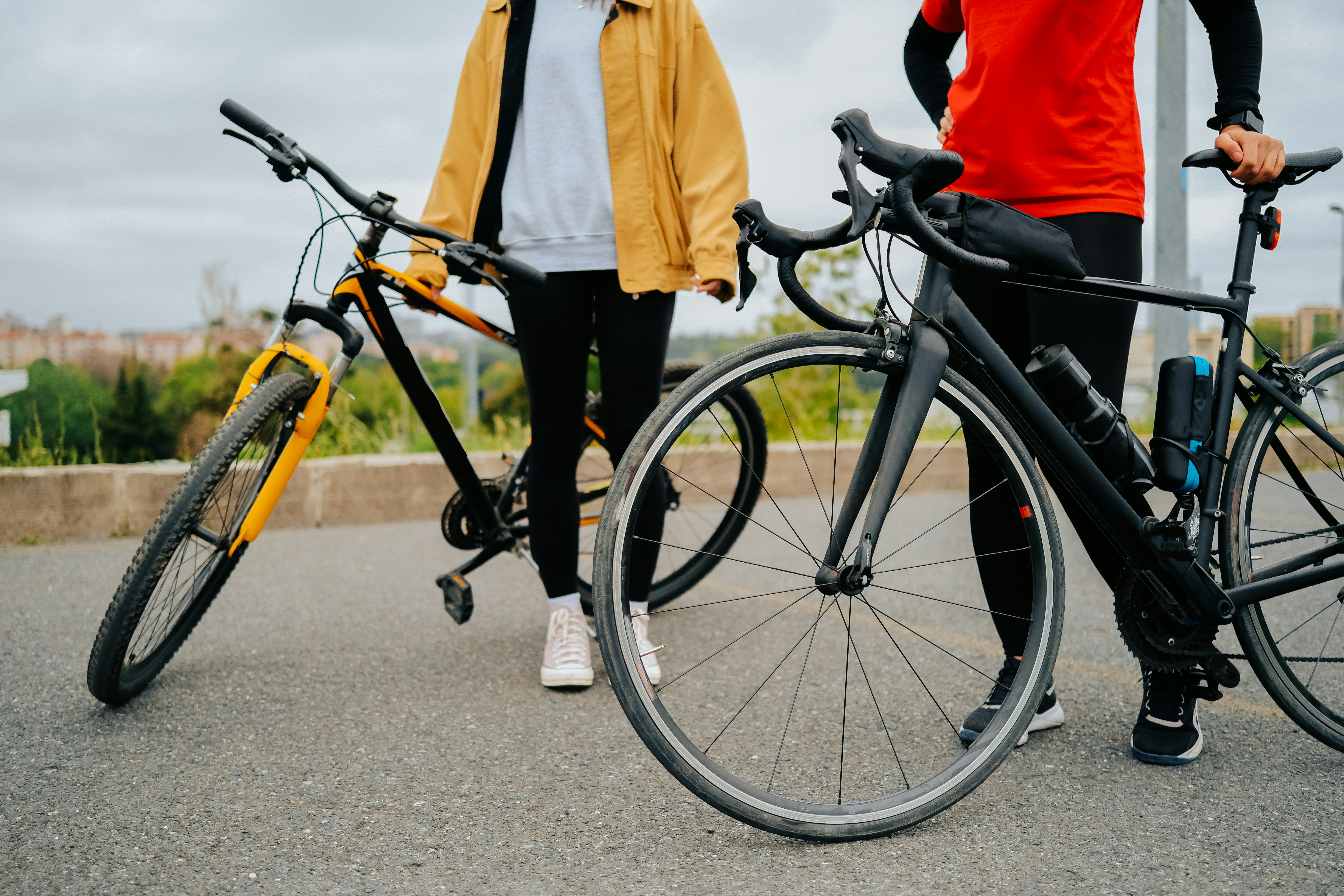 Two people standing beside their bikes in the city.