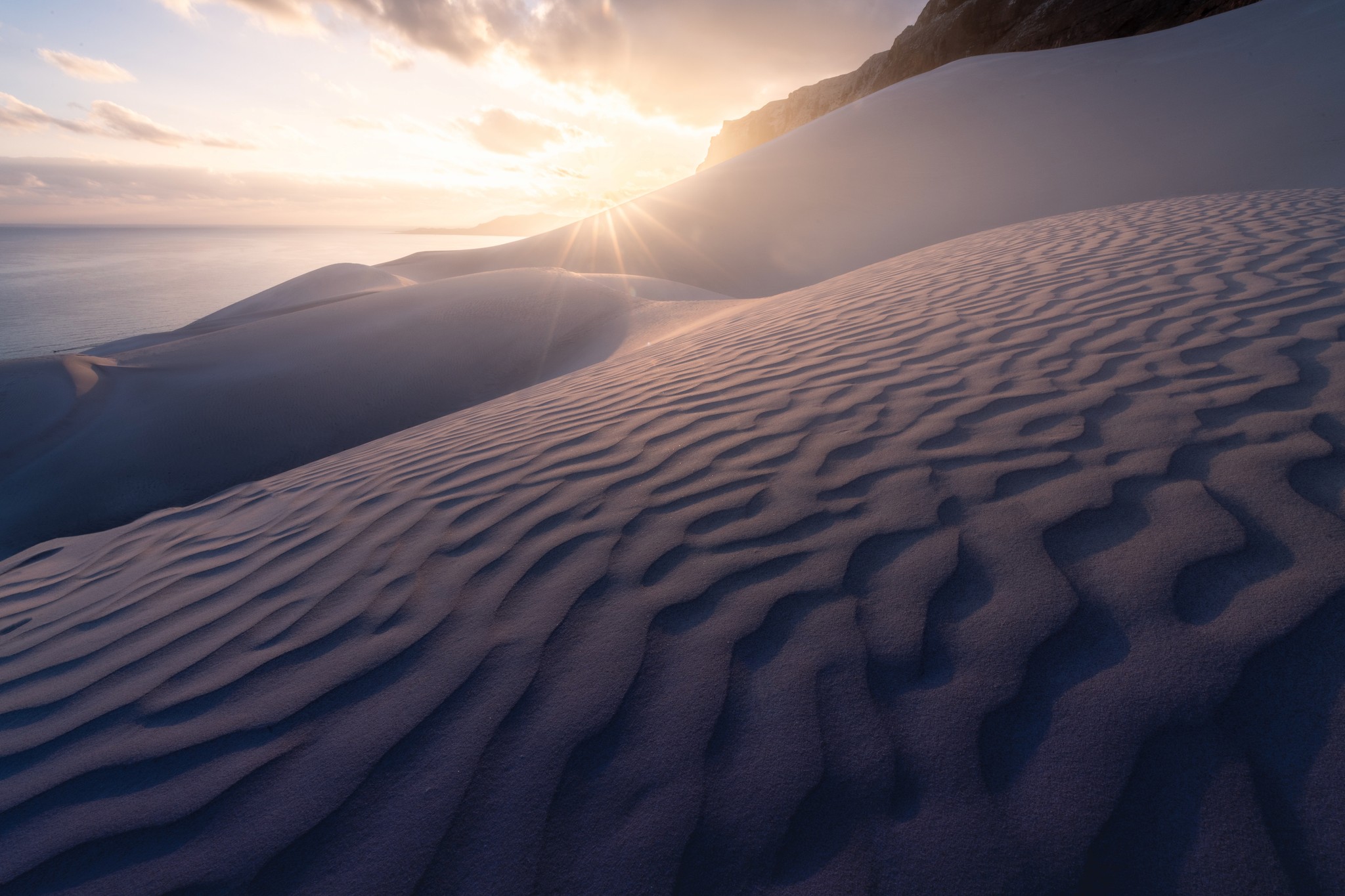 The sun peaking out over a sand dune