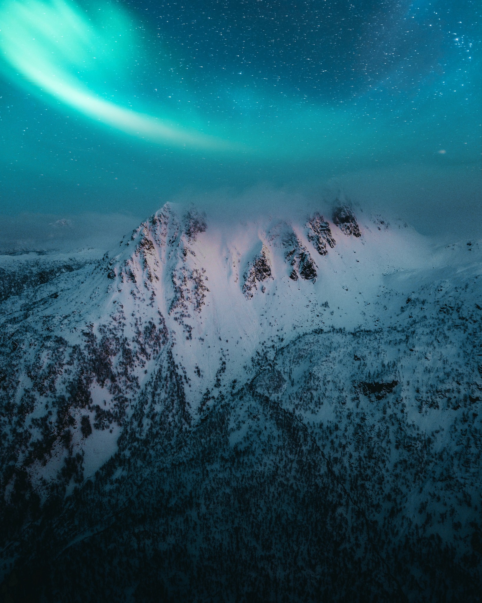 The glow of the northern lights above a snowy mountain on a clear night