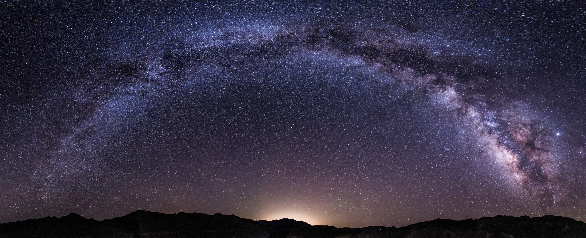 The milky way above the horizon over dark mountains