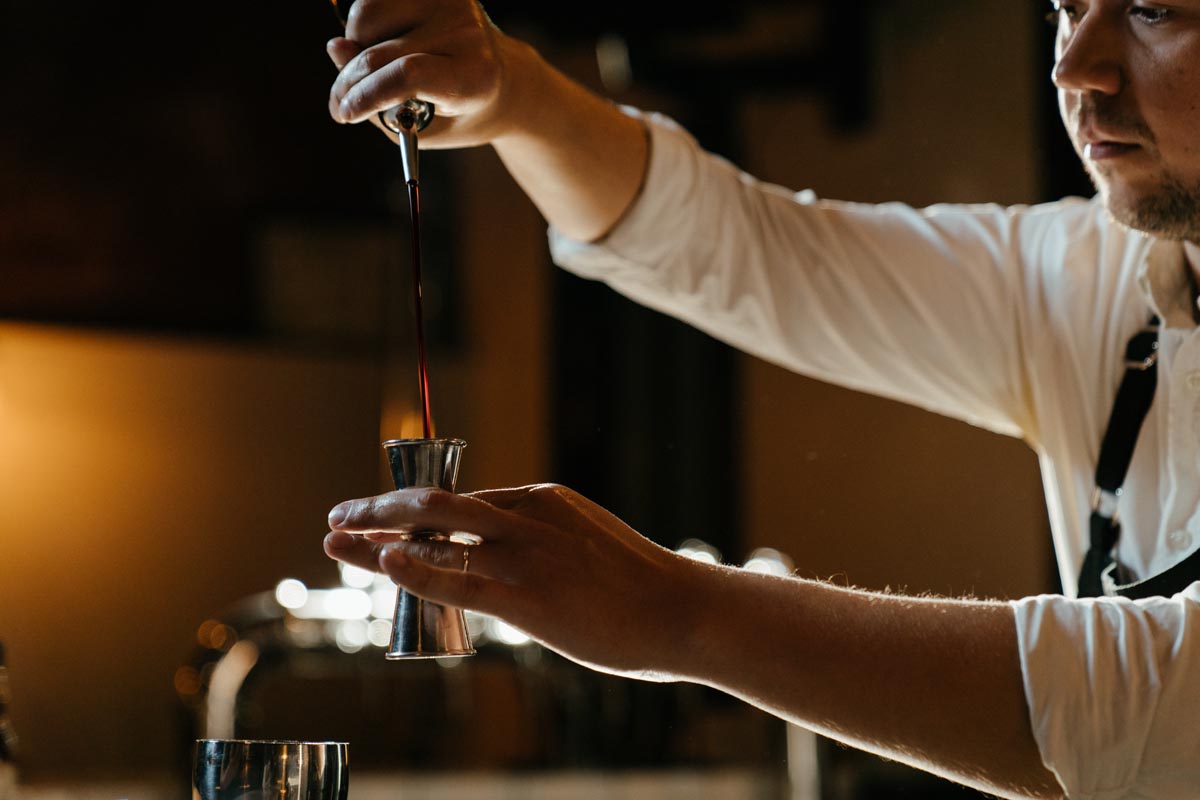 A bartender pouring liquor into a shot glass