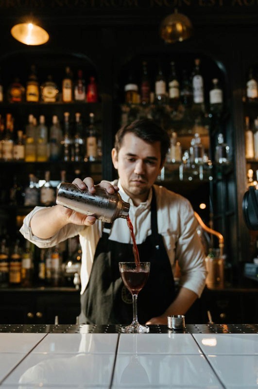 Portrait of a bartender pouring a cocktail