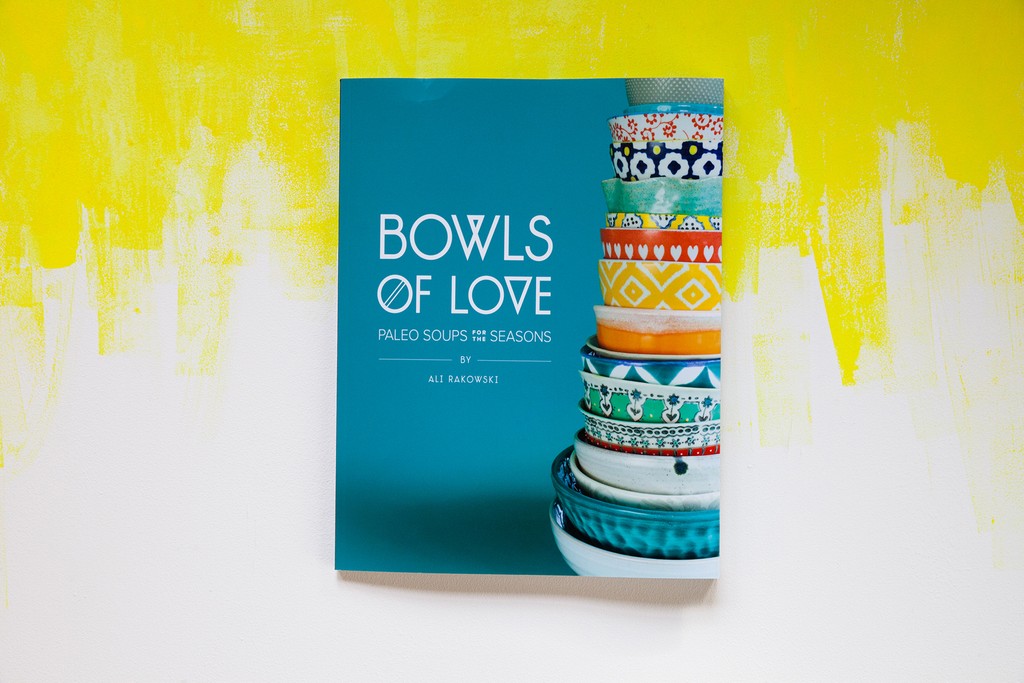 Bowls of Love cover features a colorful stack of ceramic bowls and photographed on a background with bright yellow paint strokes.