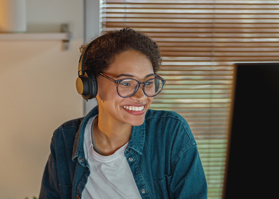 A three-quarter shot of an African lady staring and smiling at her computer screen