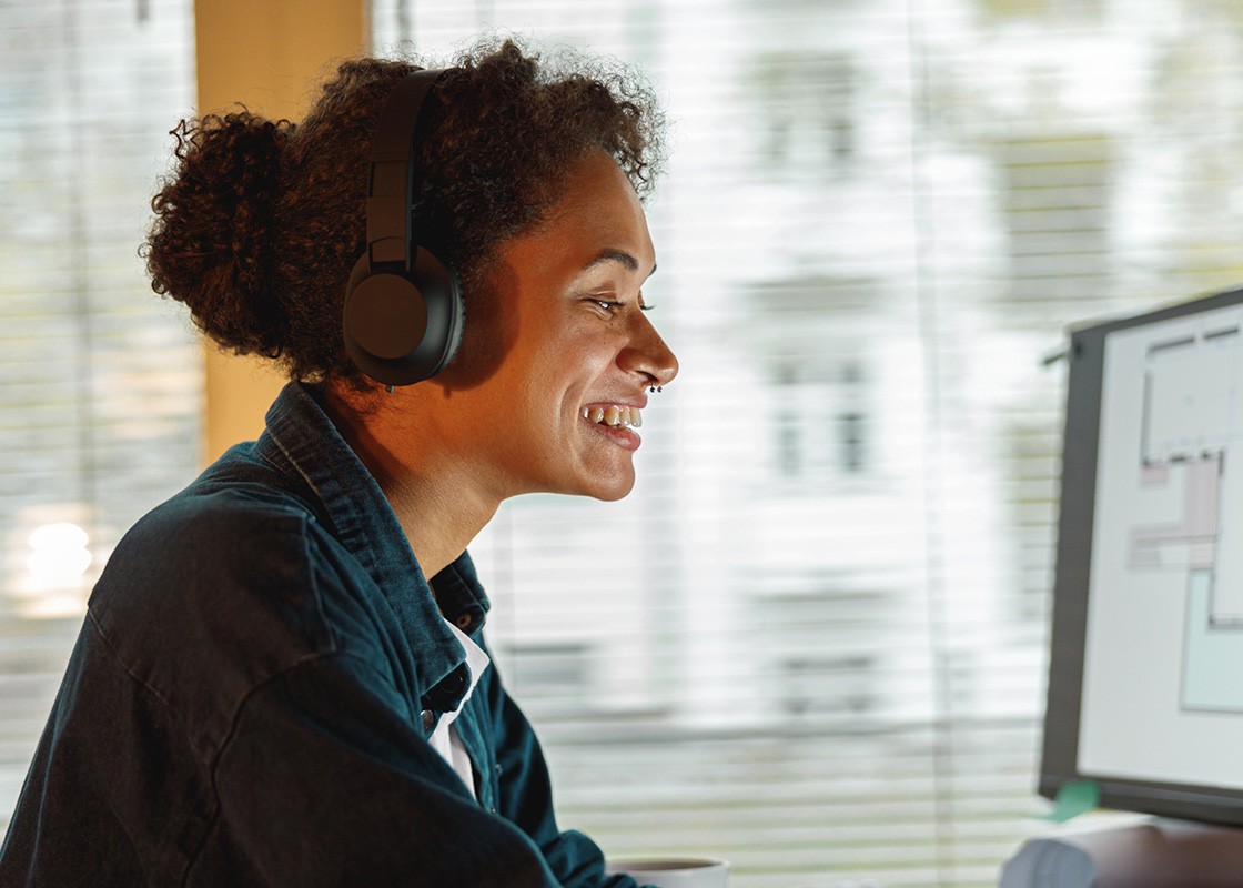 A medium shot of an African lady staring and smiling at her computer screen