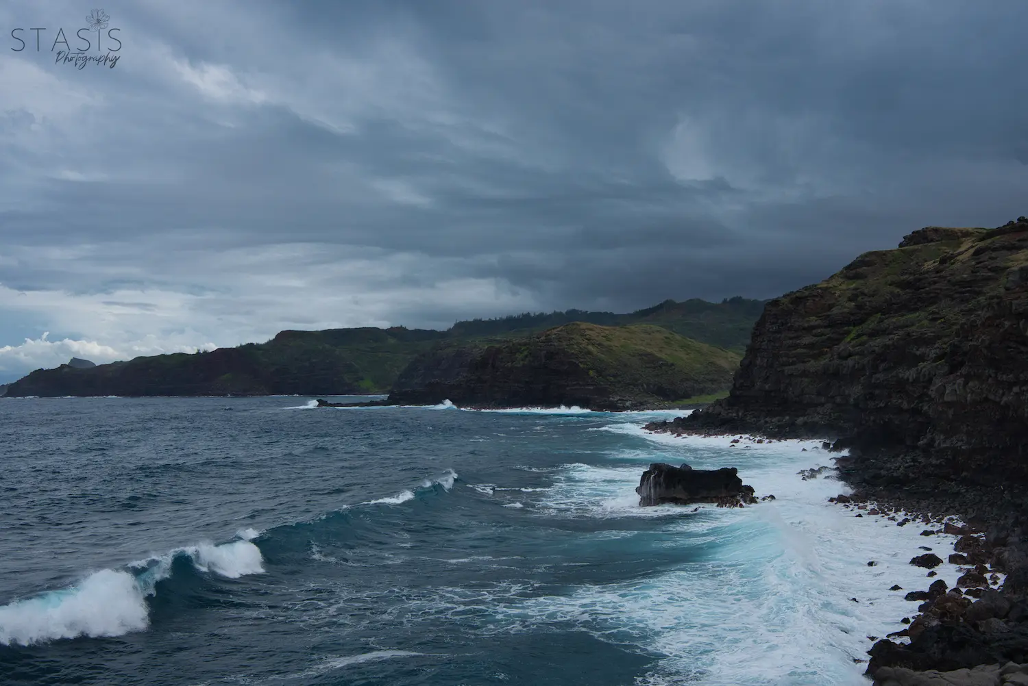 waves crashing on cliffs with storm clouds at the blow hole in maui taken by professional photographer