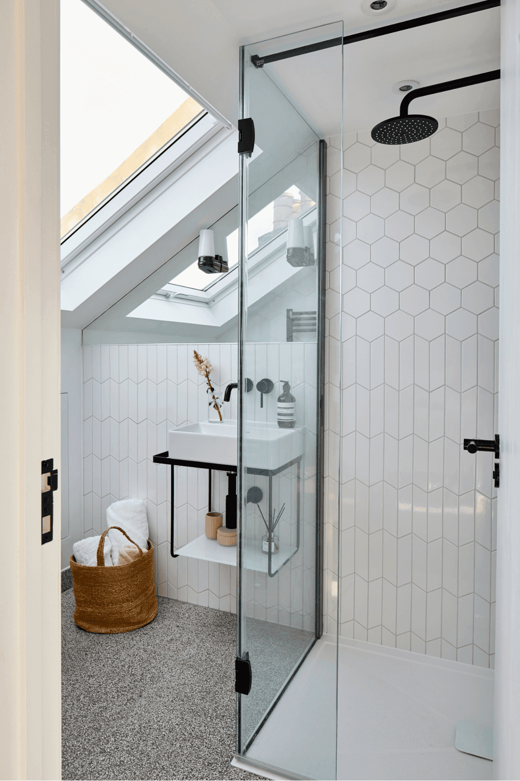 A South West London loft conversion featuring a white bathroom with a skylight over the shower.	