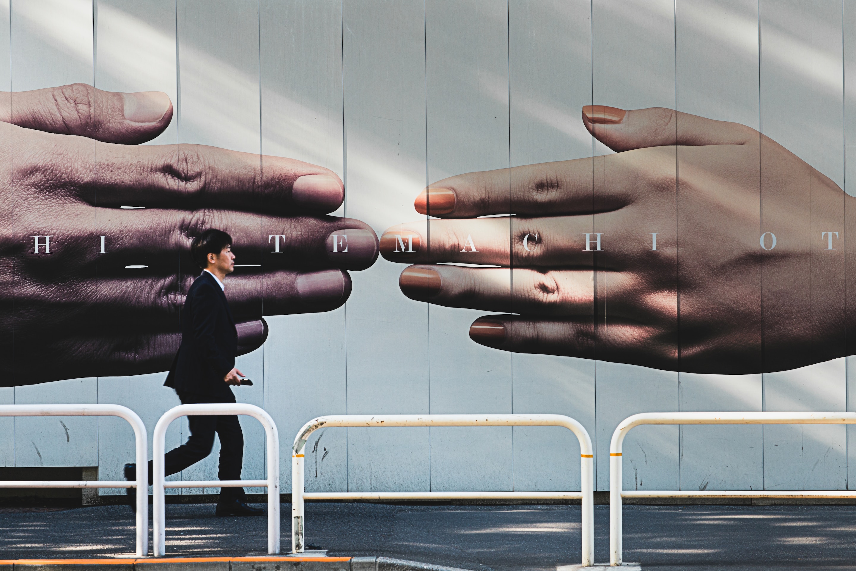 man walking past a poster touching fingers